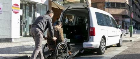 Un taxista ayuda a subir a un taxi a un usuario en silla de ruedas