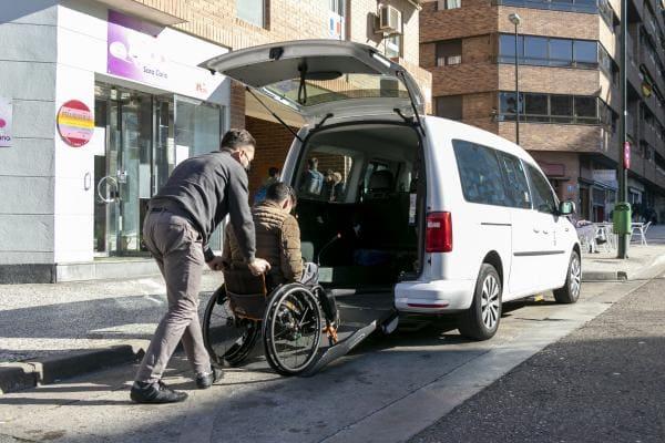 Un taxista ayuda a subir a un taxi a un usuario en silla de ruedas