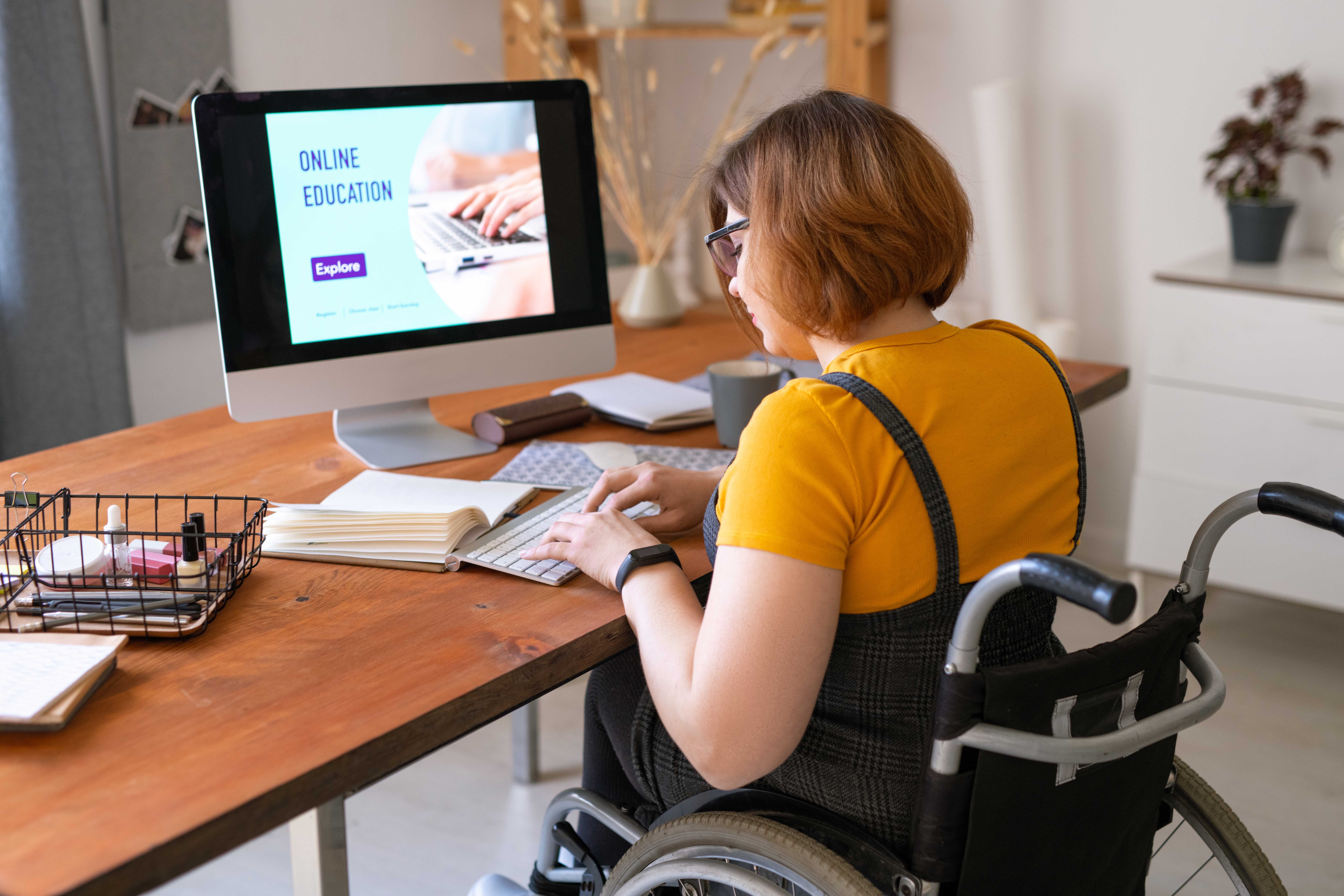 Mujer en silla de ruedas delante de un ordenador de sobremesa en una plataforma de formación